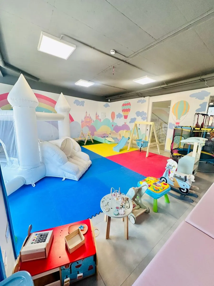 The pastel play area with a bouncy castle, slides and ride-ons at Play Cafe & Events