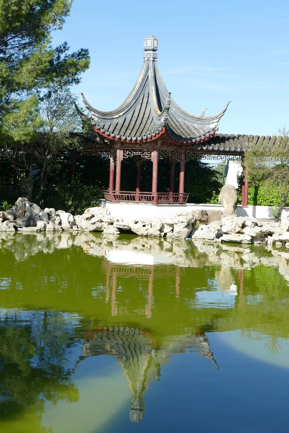 A red Chinese pavilion reflected in the pond at the Garden of Serenity