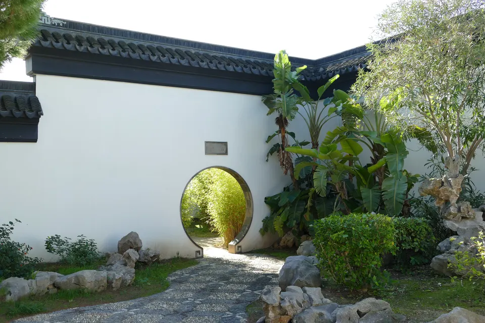 A round moon gate in a white garden wall